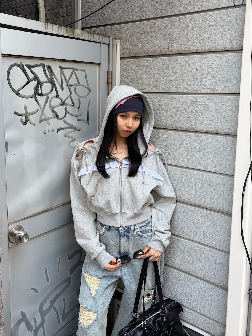 グレー系のパーカー、ブルー系のデニムパンツ、ブラック系のトートバッグを着用したレディースの春コーディネートの5枚目の写真