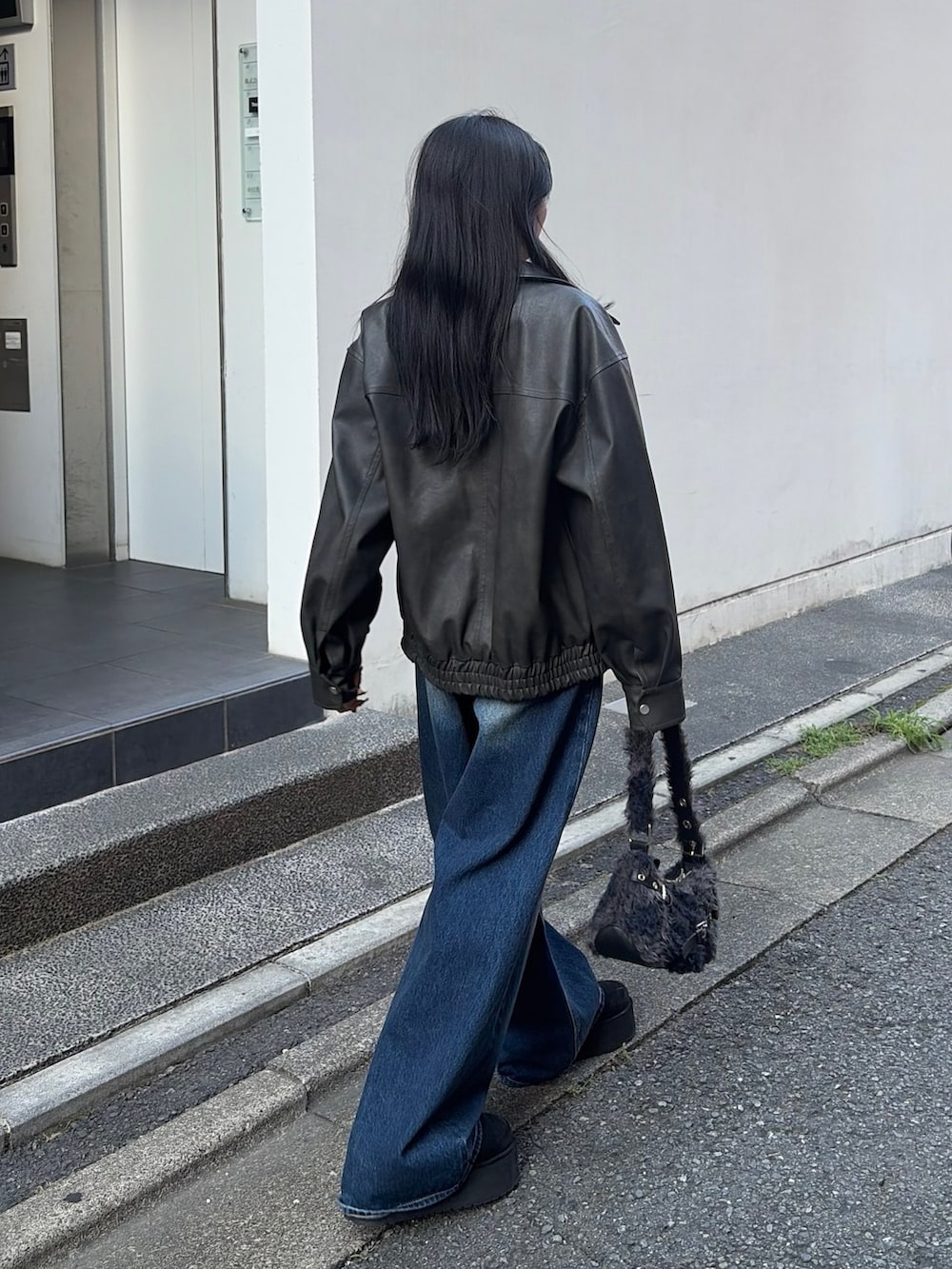 ブラック系のブルゾン、ブラック系のTシャツ/カットソー、ブルー系のデニムパンツを着用したレディースの秋コーディネートの3枚目の写真