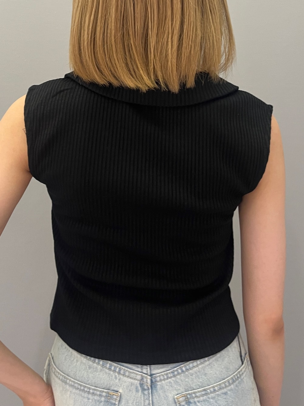 ブラック系のタンクトップ、ブラック系のショルダーバッグ、ブルー系のデニムパンツを着用したレディースの夏コーディネートの5枚目の写真