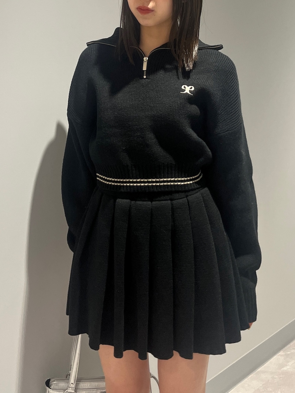 ブラック系のニット/セーター、ブラック系のスカート、ブラック系のブーツを着用したレディースの秋コーディネートの4枚目の写真