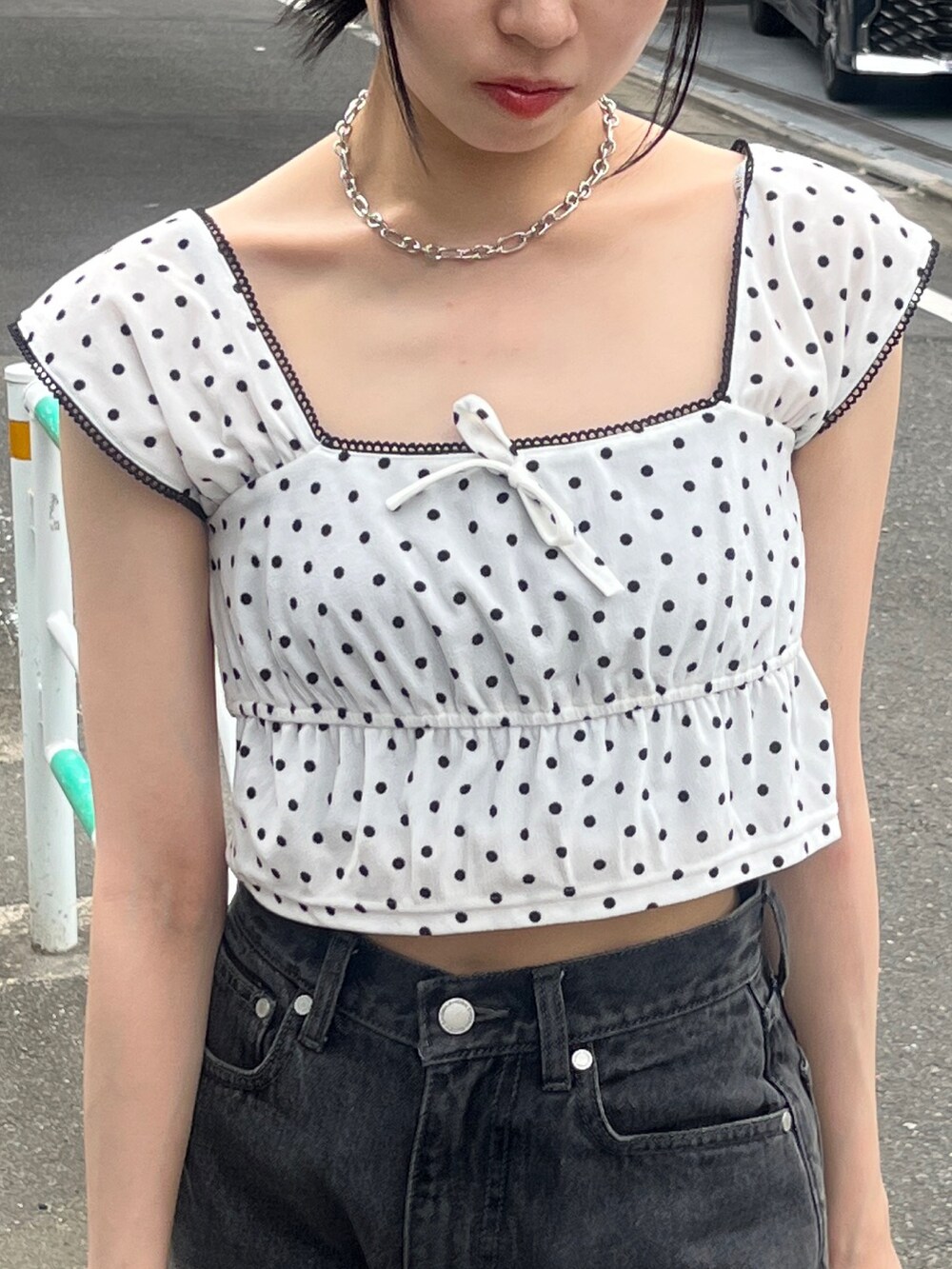 ホワイト系のタンクトップ、ブラック系のデニムパンツ、ブラック系のハンドバッグを着用したレディースの夏コーディネートの5枚目の写真