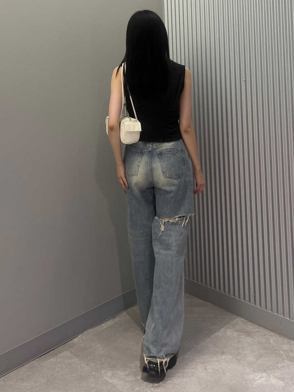 ブルー系のデニムパンツ、ホワイト系のハンドバッグ、ブラック系のTシャツ/カットソーを着用したレディースの夏コーディネートの3枚目の写真