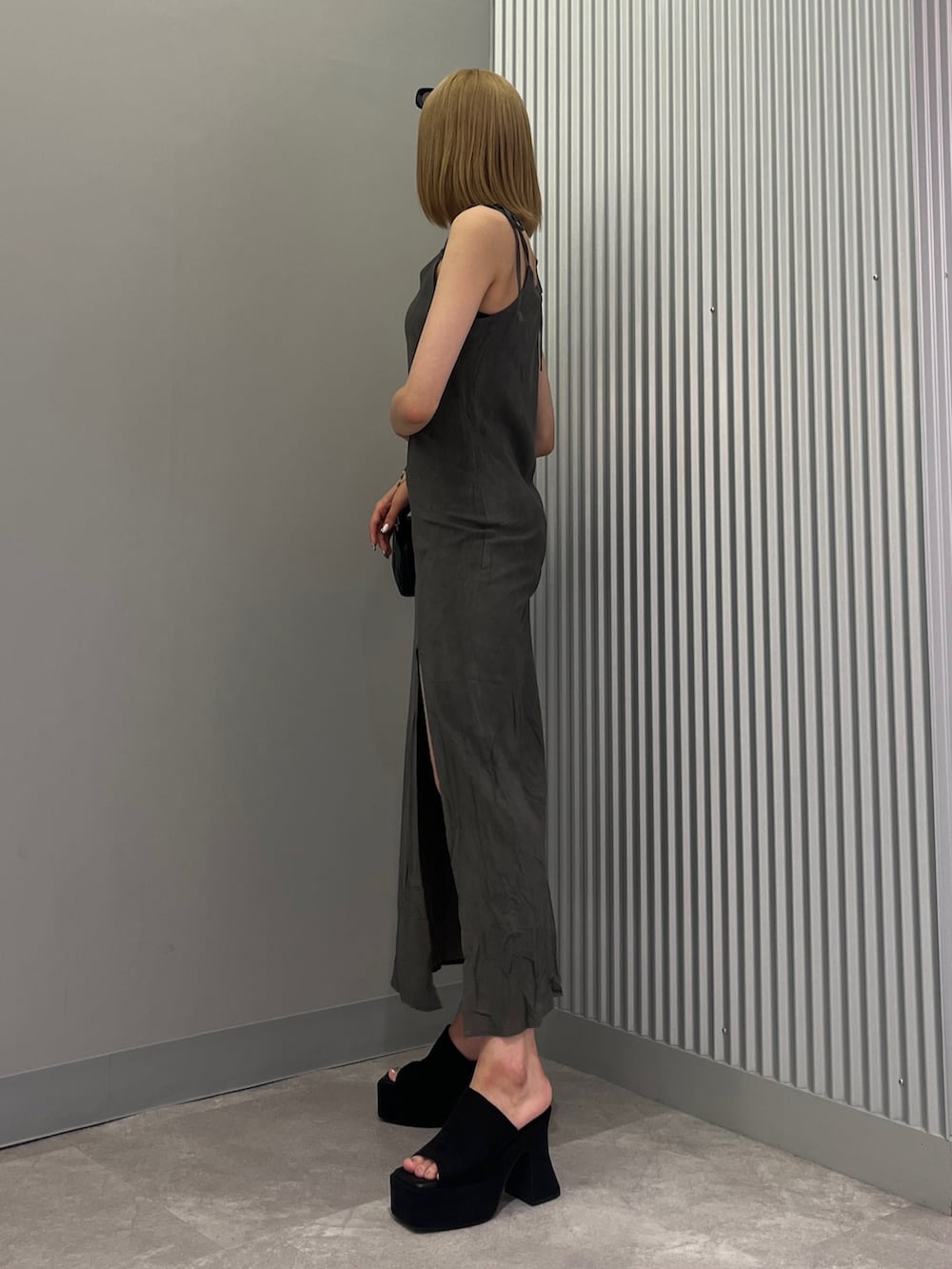 ブラック系のハンドバッグ、ブラック系のワンピース、ブラック系のサンダルを着用したレディースの夏コーディネートの2枚目の写真