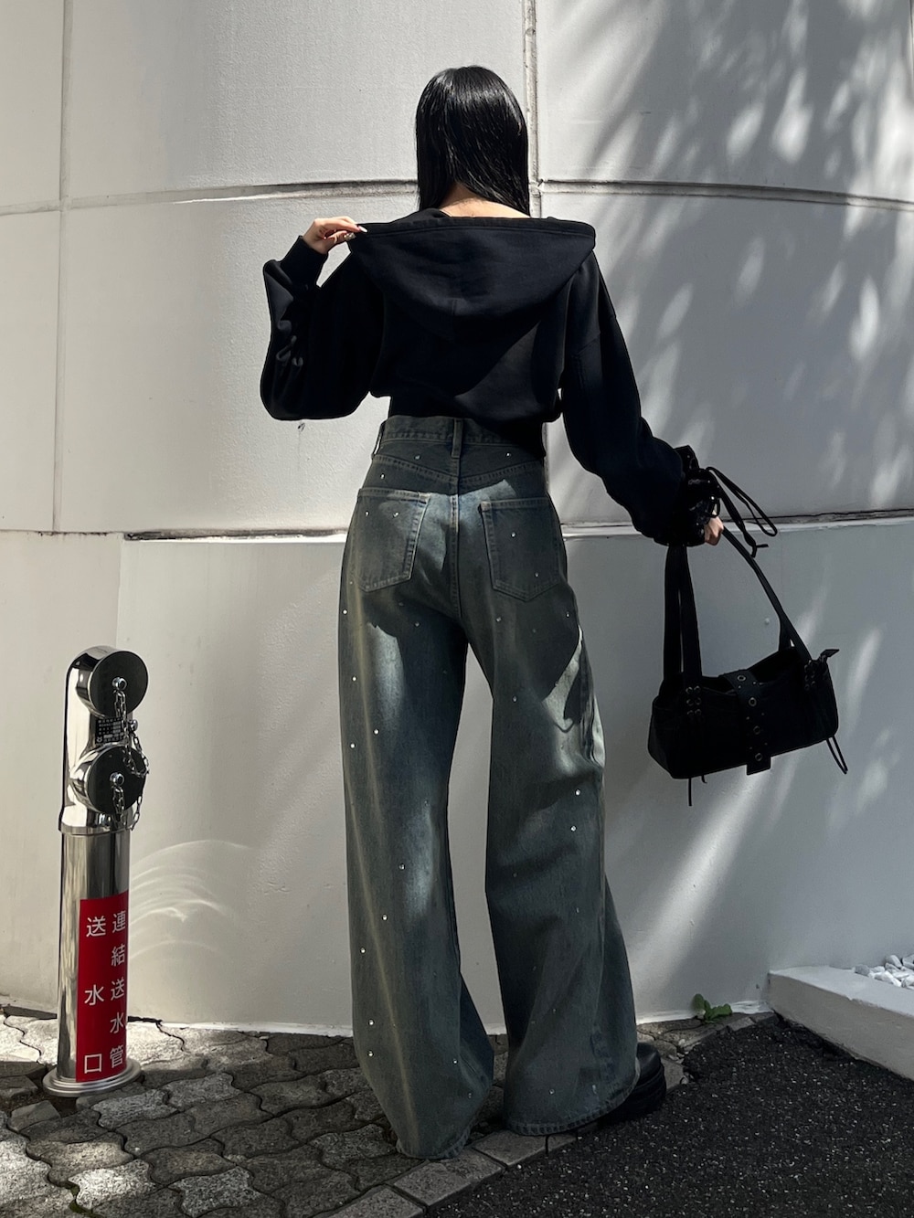 ブラック系のパーカー、ブルー系のデニムパンツ、ブラック系のハンドバッグを着用したレディースの秋コーディネートの3枚目の写真