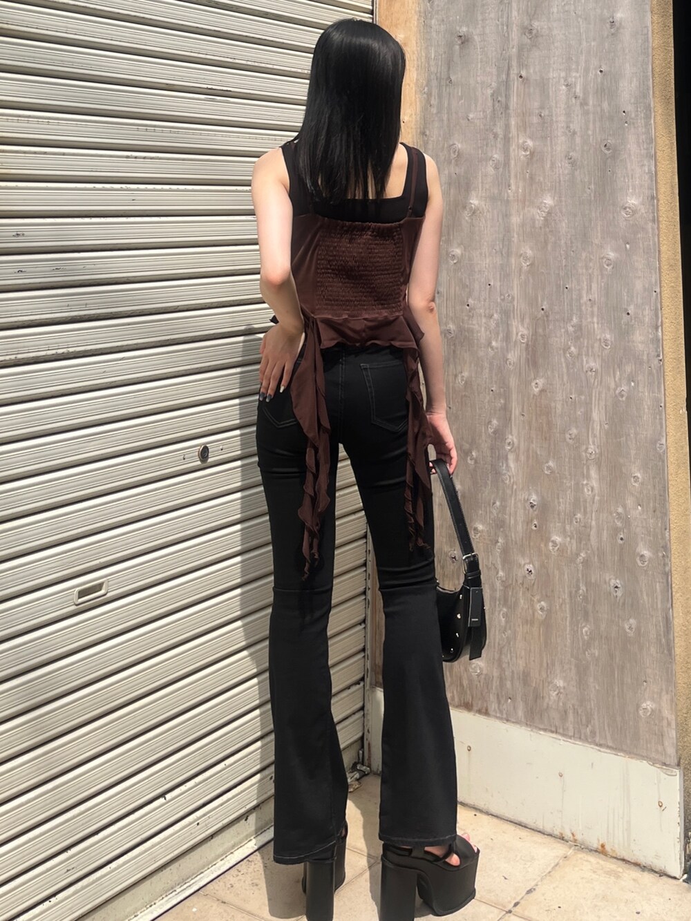 ブラック系のサロペット/オーバーオール、ブラック系のハンドバッグ、ブラック系のサンダルを着用したレディースの春コーディネートの2枚目の写真