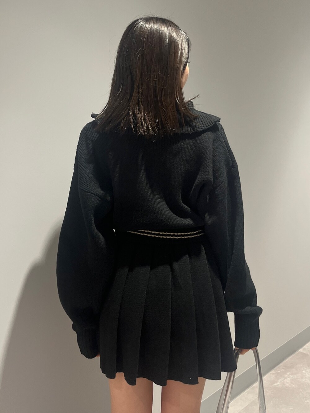 ブラック系のニット/セーター、ブラック系のスカート、ブラック系のブーツを着用したレディースの秋コーディネートの5枚目の写真