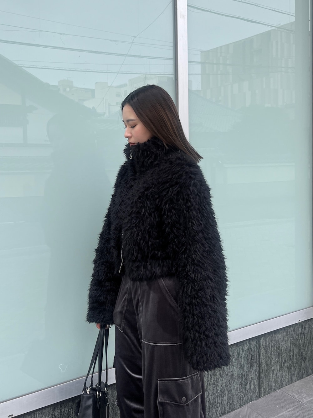 ブラック系のニット/セーター、ブラック系のブルゾン、グレー系のカーゴパンツを着用したレディースの秋コーディネートの6枚目の写真