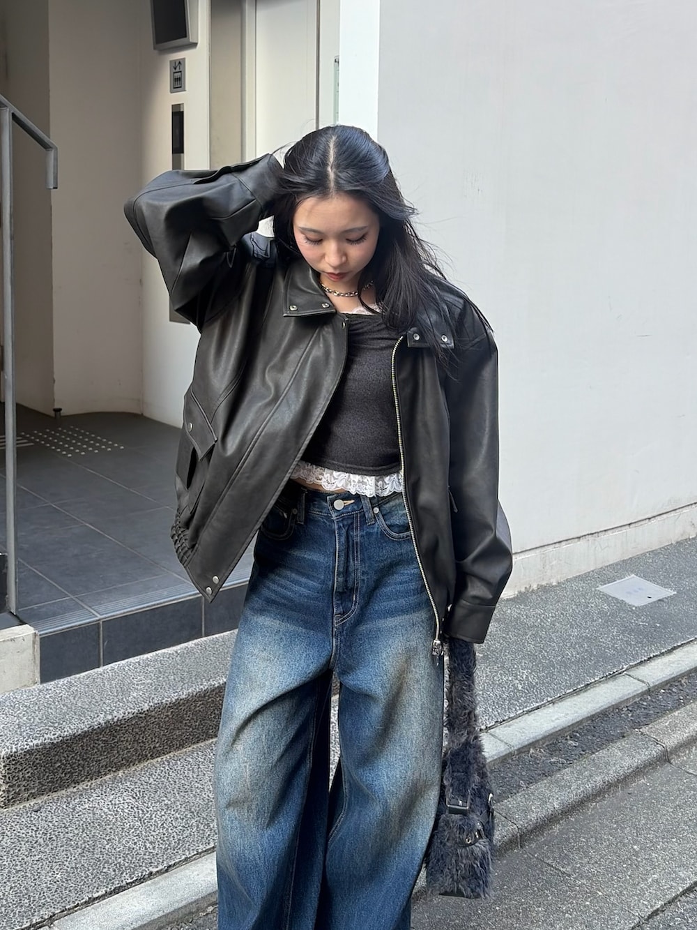 ブラック系のブルゾン、ブラック系のTシャツ/カットソー、ブルー系のデニムパンツを着用したレディースの秋コーディネートの4枚目の写真