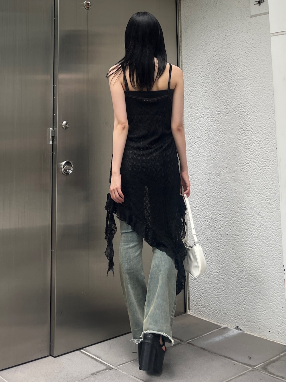 ブルー系のデニムパンツ、ホワイト系のショルダーバッグ、ブラック系のサンダルを着用したレディースの夏コーディネートの3枚目の写真