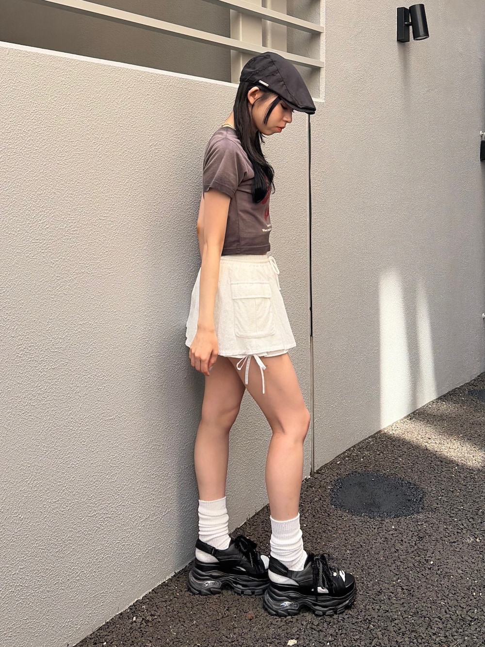 ブラック系のTシャツ/カットソー、ホワイト系のスカート、ブラック系のサンダルを着用したレディースの夏コーディネートの3枚目の写真