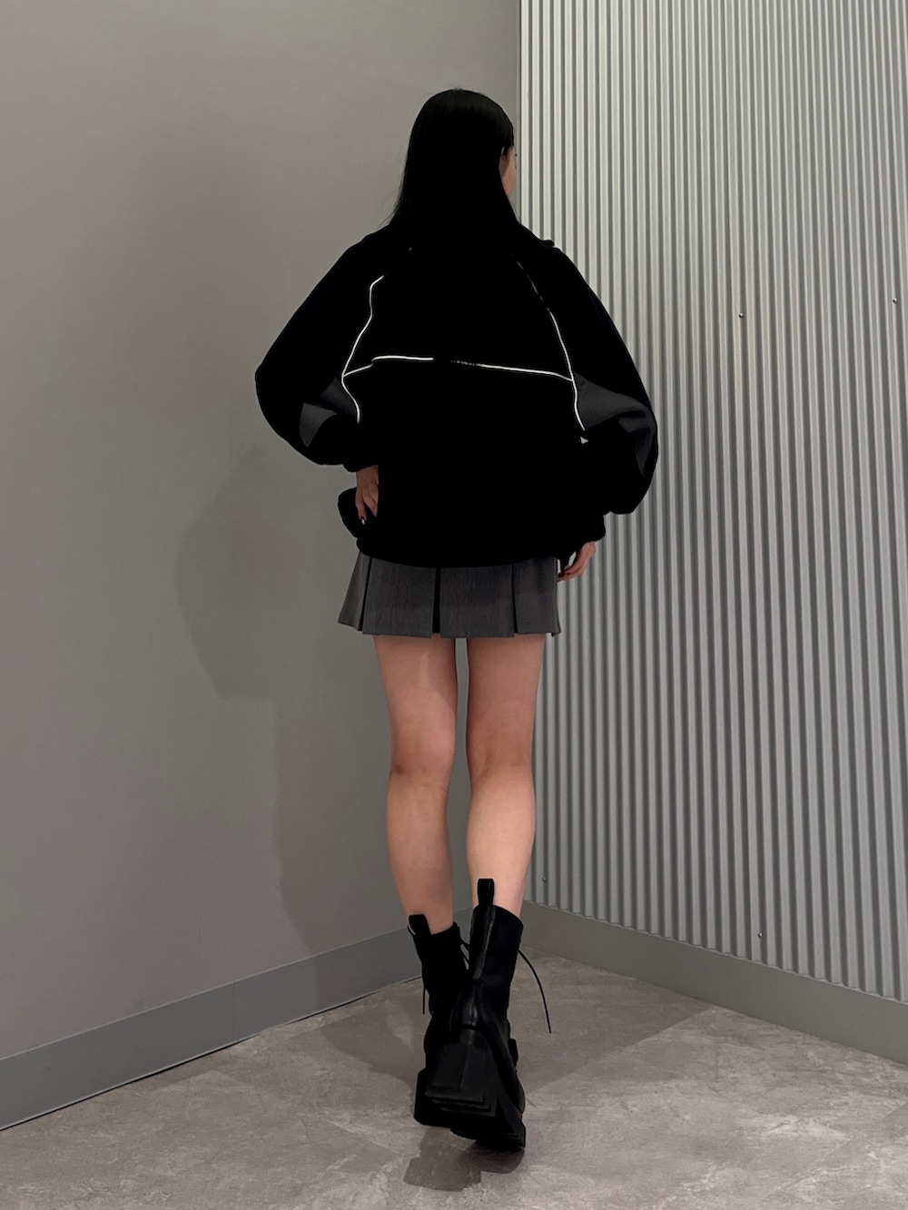 ブラック系のTシャツ/カットソー、グレー系のスカート、ブラック系のブーツを着用したレディースの冬コーディネートの2枚目の写真