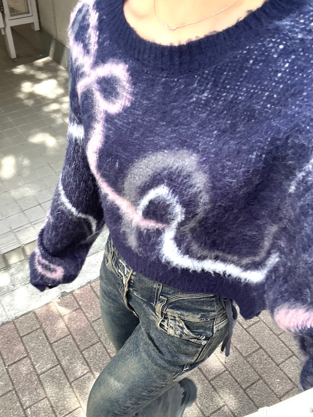 ブルー系のニット/セーター、ブルー系のデニムパンツ、ホワイト系のショルダーバッグを着用したレディースの秋コーディネートの4枚目の写真