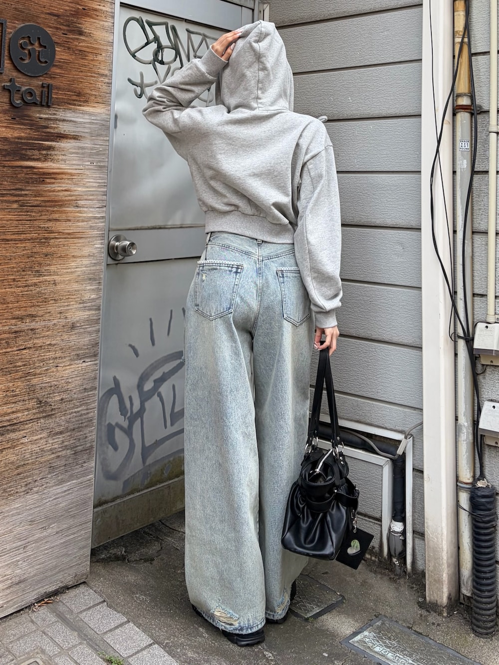 グレー系のパーカー、ブルー系のデニムパンツ、ブラック系のトートバッグを着用したレディースの春コーディネートの3枚目の写真