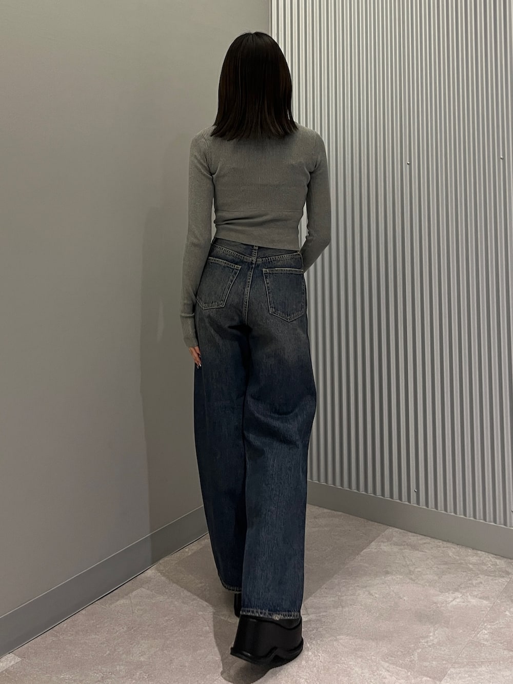 グレー系のニット/セーター、ブルー系のデニムパンツ、ブラック系のショルダーバッグを着用したレディースの秋コーディネートの3枚目の写真