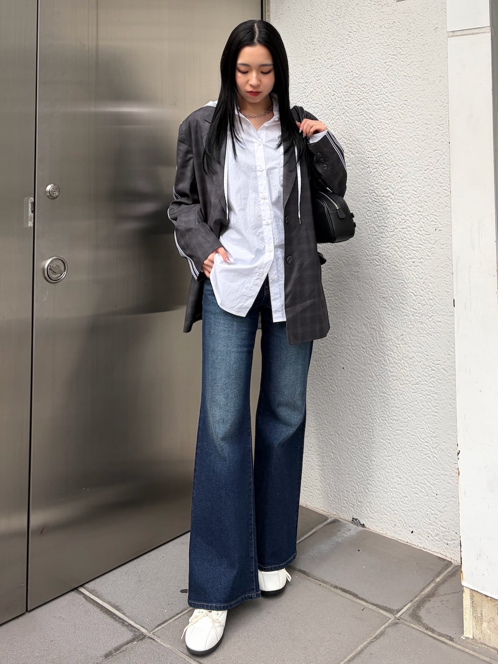 グレー系のテーラードジャケット、ホワイト系のシャツ/ブラウス、ブルー系のデニムパンツを着用したレディースの春コーディネートの3枚目の写真
