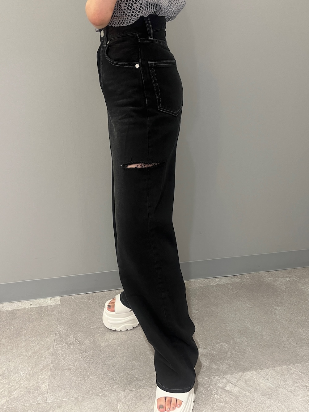 ブラック系のデニムパンツ、グレー系のTシャツ/カットソー、ホワイト系のサンダルを着用したレディースの夏コーディネートの8枚目の写真