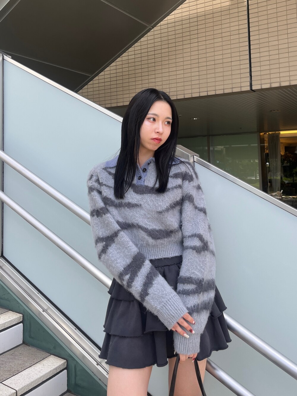 グレー系のニット/セーター、グレー系のスカート、ブラック系のブーツを着用したレディースの秋コーディネートの4枚目の写真