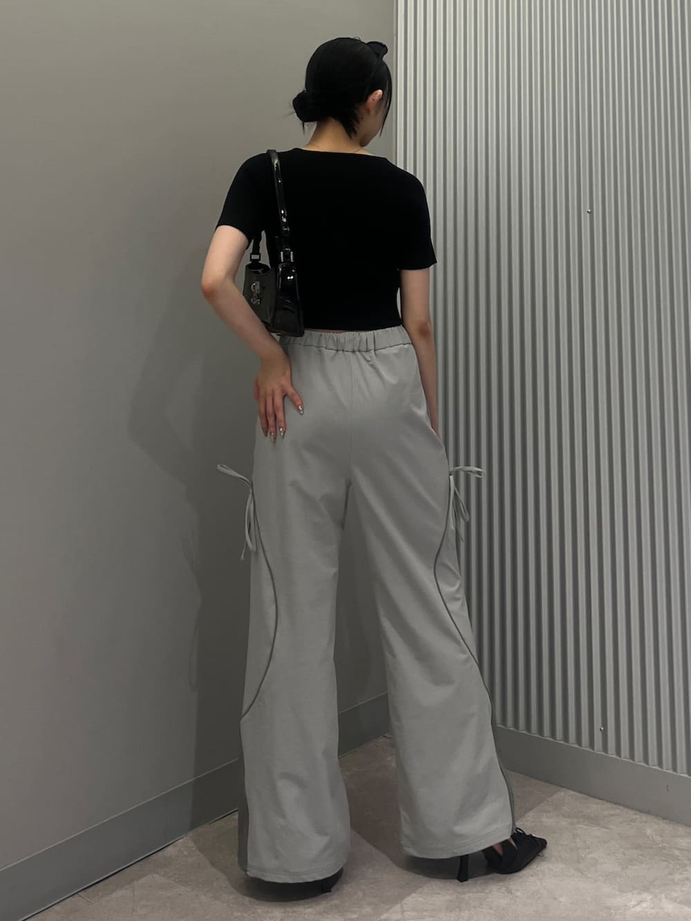 ブラック系のショルダーバッグ、グレー系のその他パンツ、ブラック系のパンプスを着用したレディースの夏コーディネートの3枚目の写真