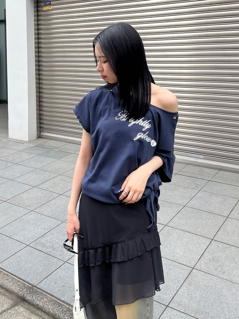 ブルー系のTシャツ/カットソー、ブラック系のスカート、ブルー系のデニムパンツを着用したレディースの春コーディネートの4枚目の写真