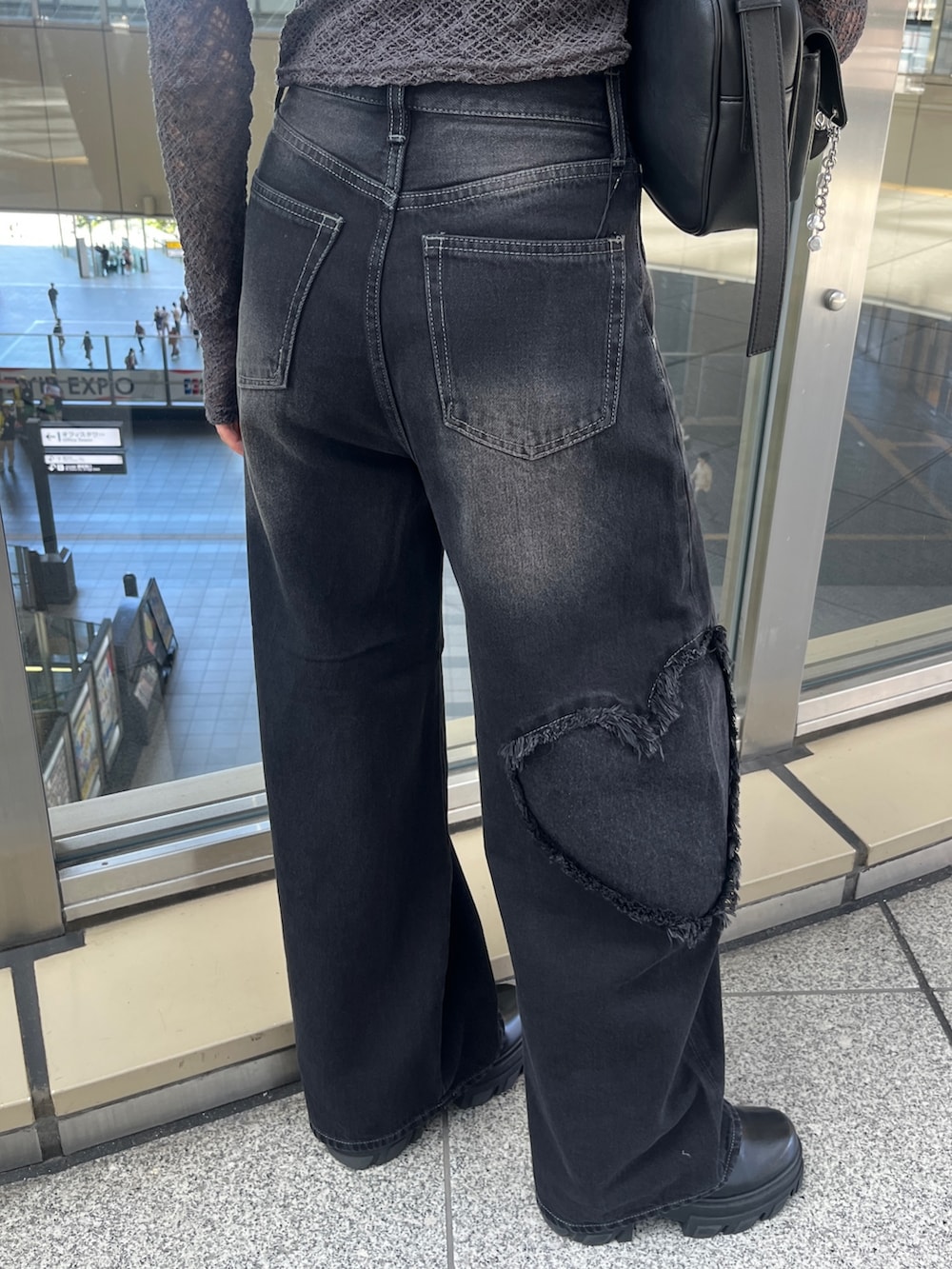 グレー系のTシャツ/カットソー、ブラック系のハンドバッグ、ブラック系のデニムパンツを着用したレディースの秋コーディネートの5枚目の写真