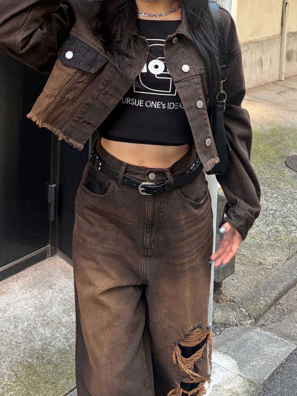 ブラック系のTシャツ/カットソー、ブラウン系のデニムパンツ、ブラック系のハンドバッグを着用したレディースの秋コーディネートの4枚目の写真