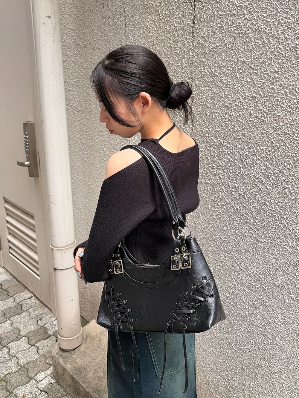 ブラック系のニット/セーター、ブルー系のデニムパンツ、ブラック系のショルダーバッグを着用したレディースの秋コーディネートの5枚目の写真