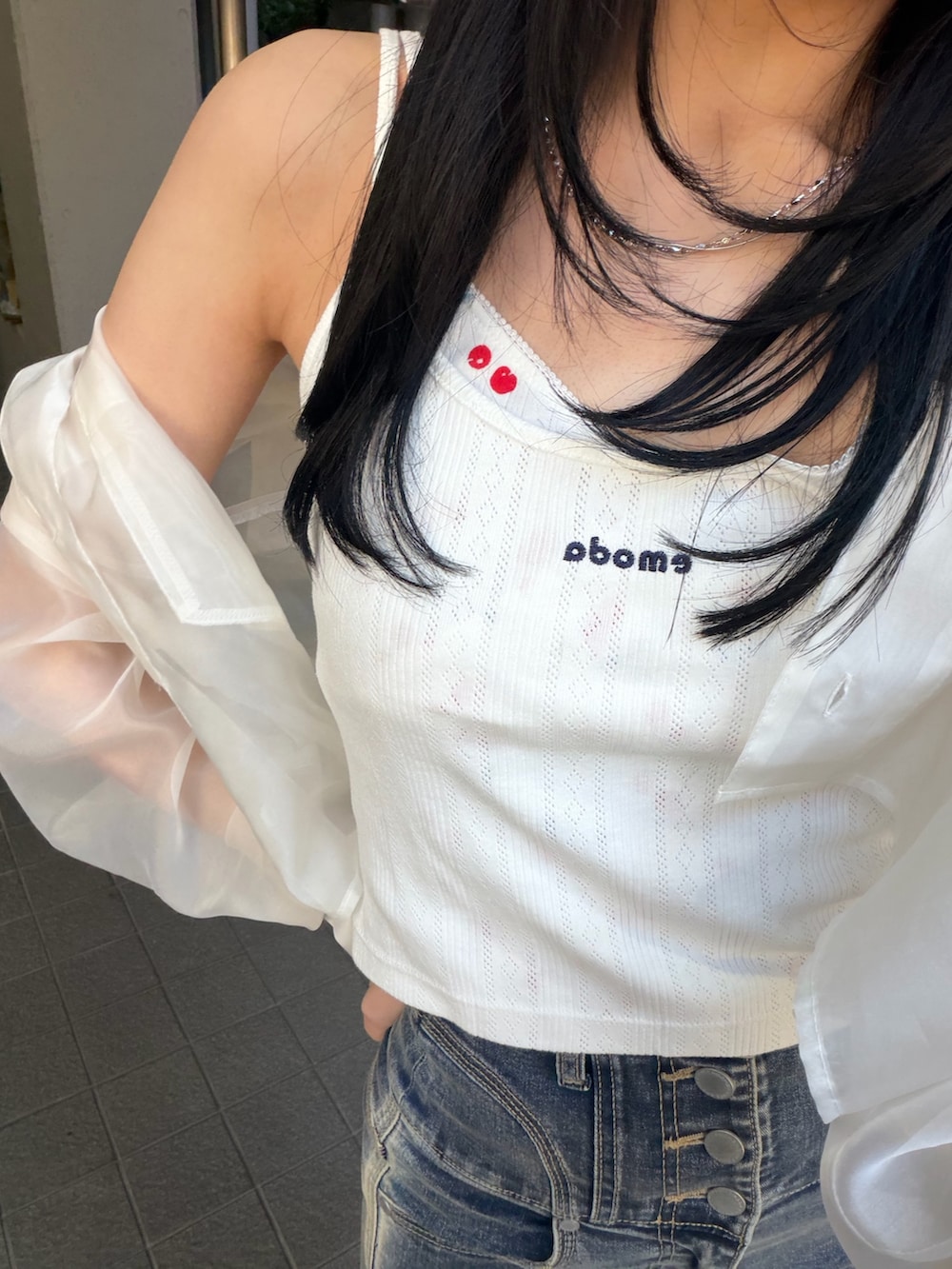 ブルー系のデニムパンツ、ブラック系のサンダル、ホワイト系のキャミソールを着用したレディースの春コーディネートの5枚目の写真