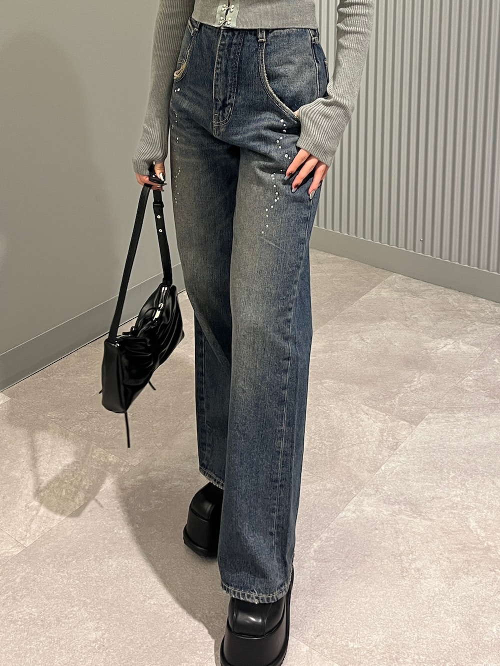 グレー系のニット/セーター、ブルー系のデニムパンツ、ブラック系のショルダーバッグを着用したレディースの秋コーディネートの7枚目の写真