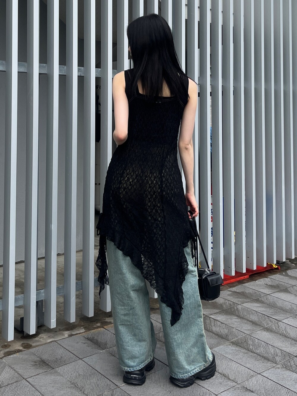 ブラック系のワンピース、ブルー系のデニムパンツ、ブラック系のサンダルを着用したレディースの夏コーディネートの3枚目の写真