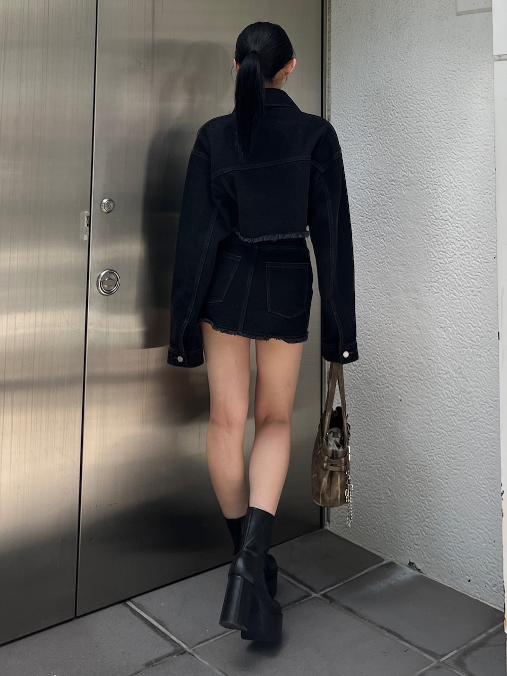 ブラック系のデニムジャケット、ブラック系のスカート、レッド系のTシャツ/カットソーを着用したレディースの夏コーディネートの2枚目の写真