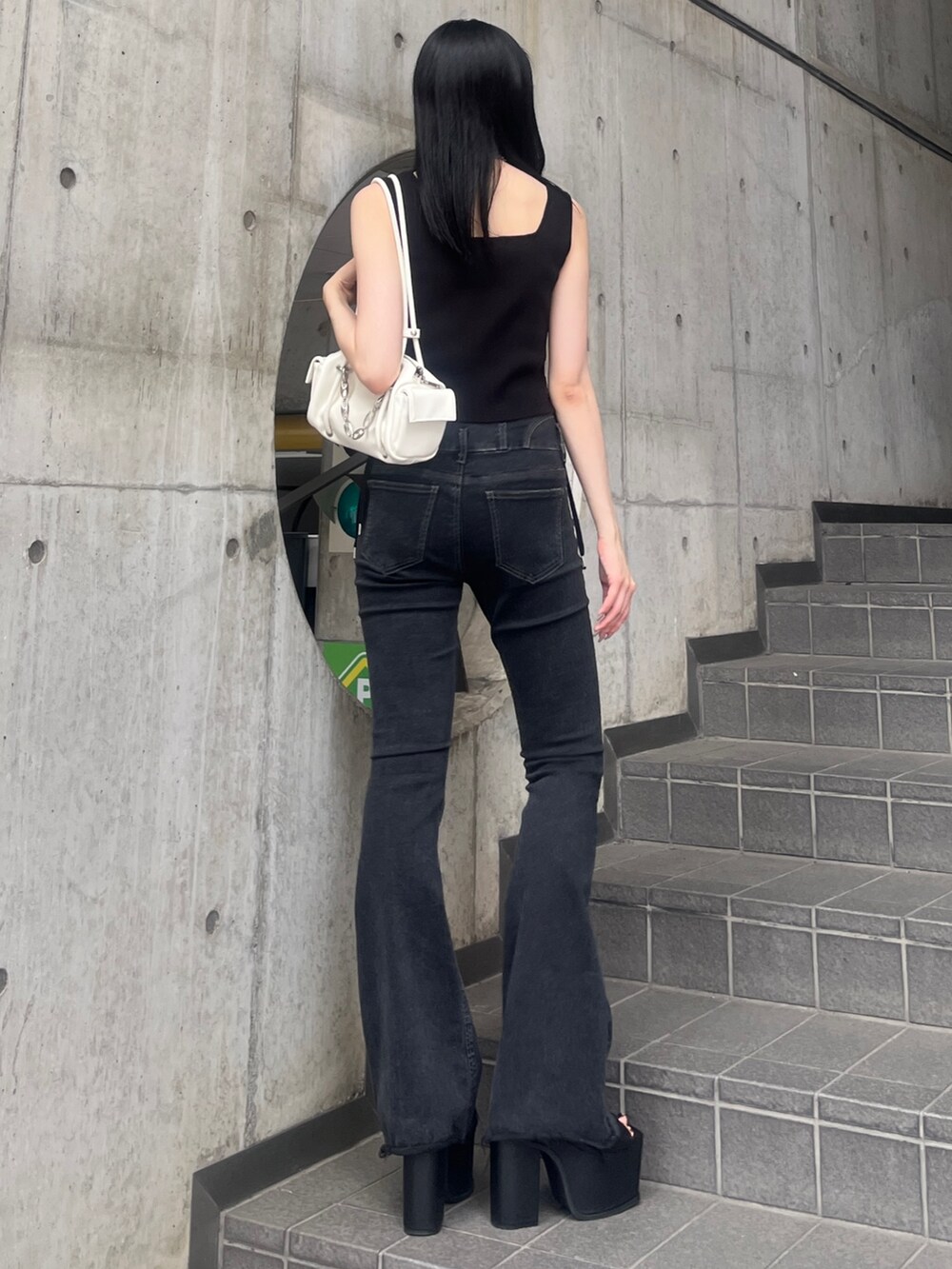 ブラック系のデニムパンツ、ブラック系のサンダル、ホワイト系のハンドバッグを着用したレディースの夏コーディネートの3枚目の写真