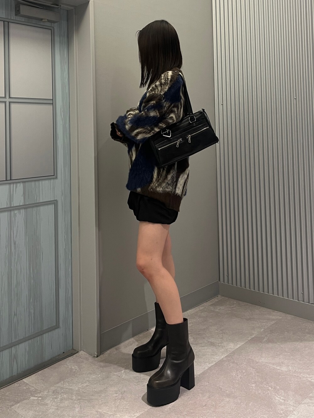 ブラウン系のニット/セーター、ブラック系のショルダーバッグ、ブラック系のスカートを着用したレディースの秋コーディネートの2枚目の写真