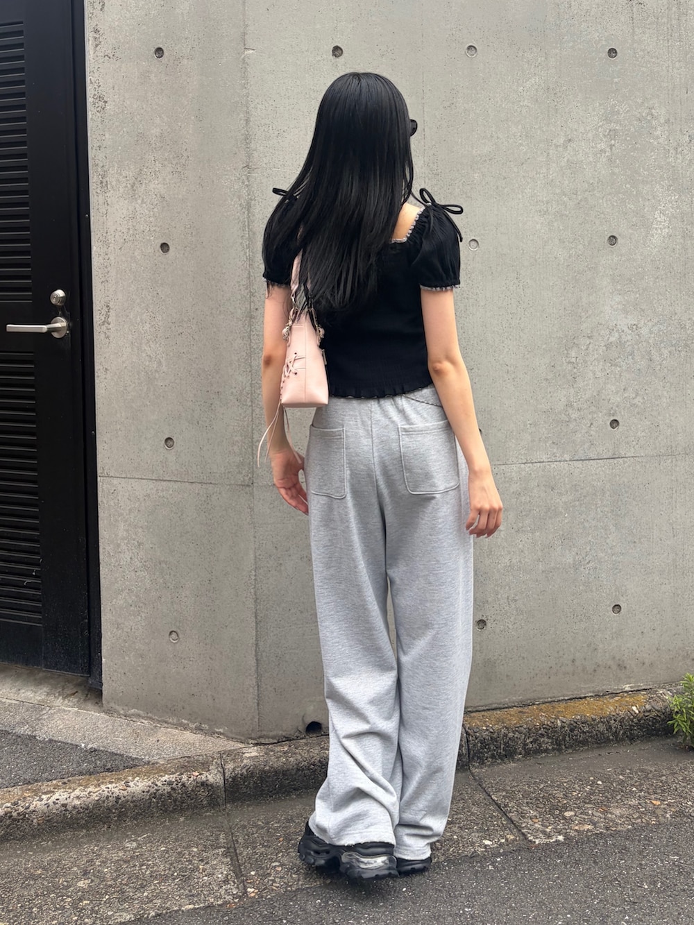 グレー系のスウェットパンツ、ブラック系のTシャツ/カットソー、ピンク系のショルダーバッグを着用したレディースの夏コーディネートの3枚目の写真