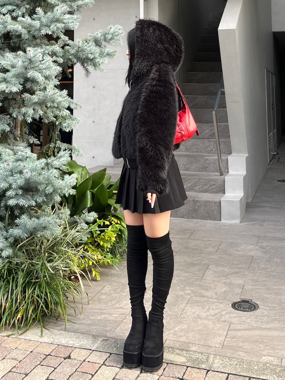 ブラック系のスカート、ブラック系のブルゾン、レッド系のショルダーバッグを着用したレディースの秋コーディネートの2枚目の写真