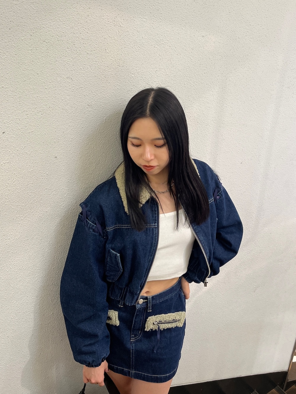 ブルー系のスカート、ブルー系のブルゾン、ホワイト系のTシャツ/カットソーを着用したレディースの秋コーディネートの4枚目の写真