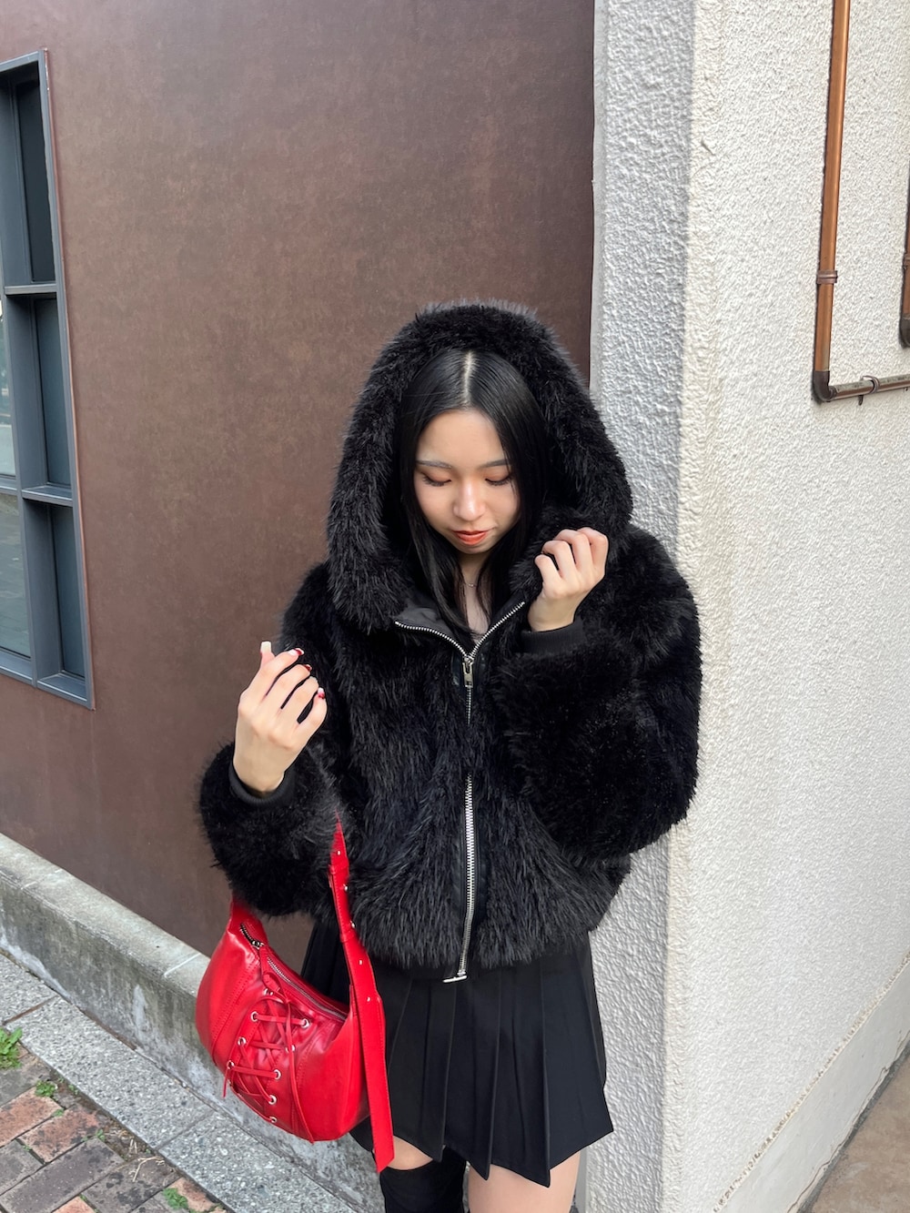 ブラック系のスカート、ブラック系のブルゾン、レッド系のショルダーバッグを着用したレディースの秋コーディネートの4枚目の写真