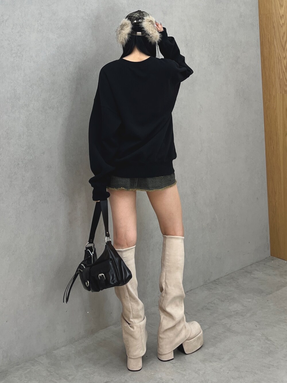 ブラック系のスウェット、ブルー系のスカート、ブラック系のハンドバッグを着用したレディースの秋コーディネートの3枚目の写真