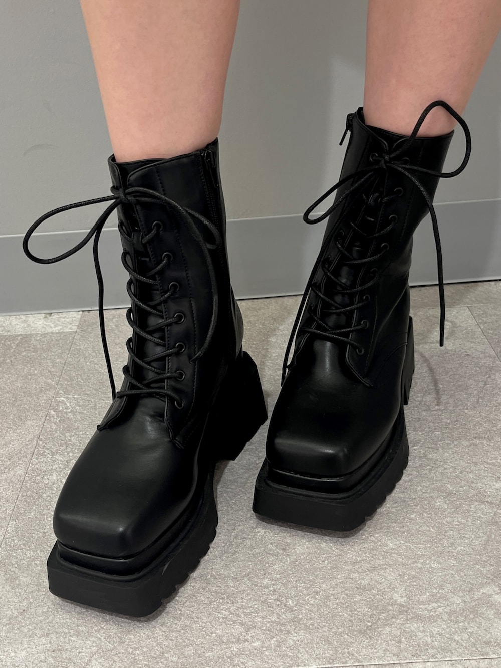 ブラック系のTシャツ/カットソー、グレー系のスカート、ブラック系のブーツを着用したレディースの冬コーディネートの3枚目の写真