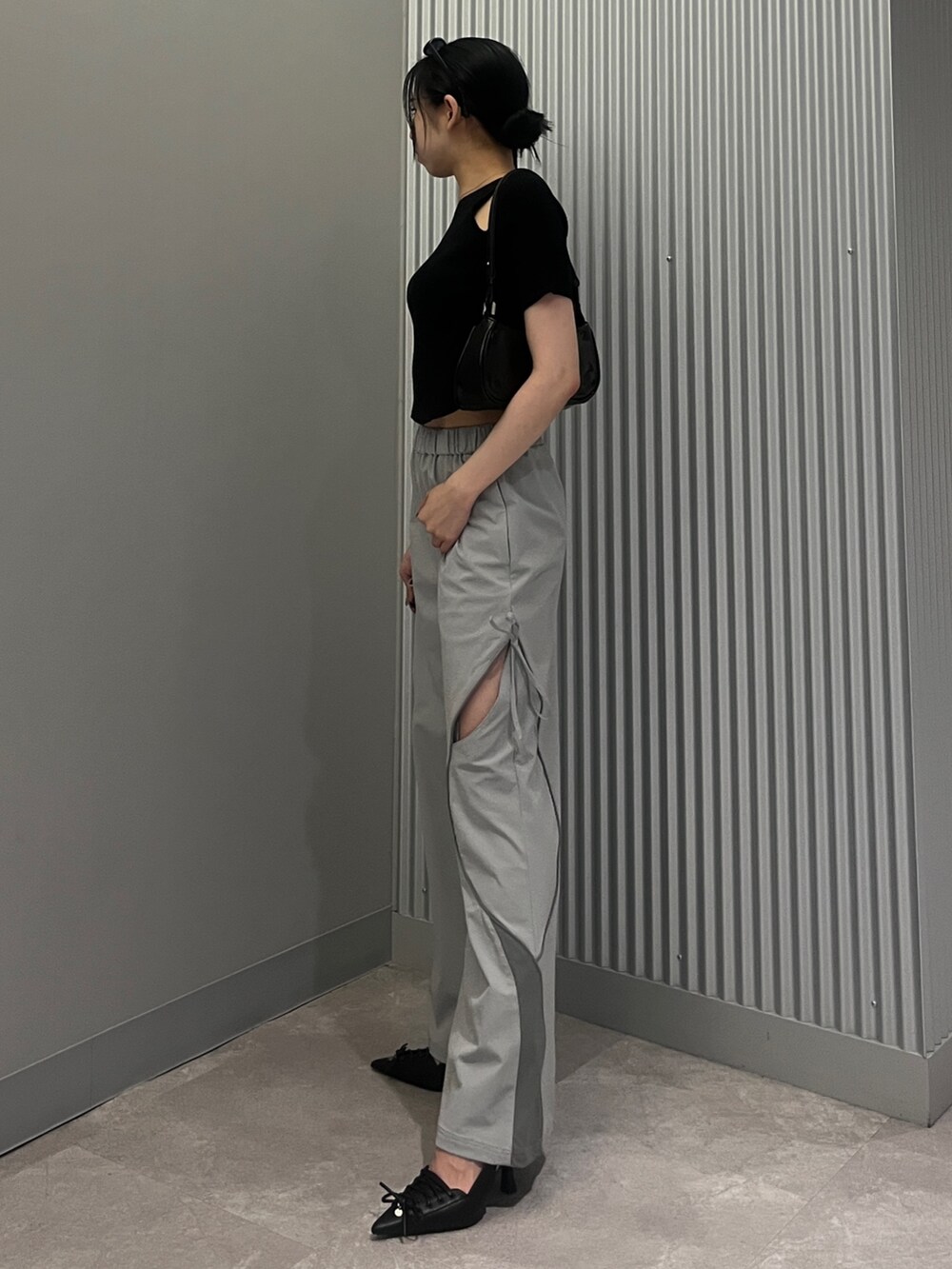 ブラック系のショルダーバッグ、グレー系のその他パンツ、ブラック系のパンプスを着用したレディースの夏コーディネートの2枚目の写真