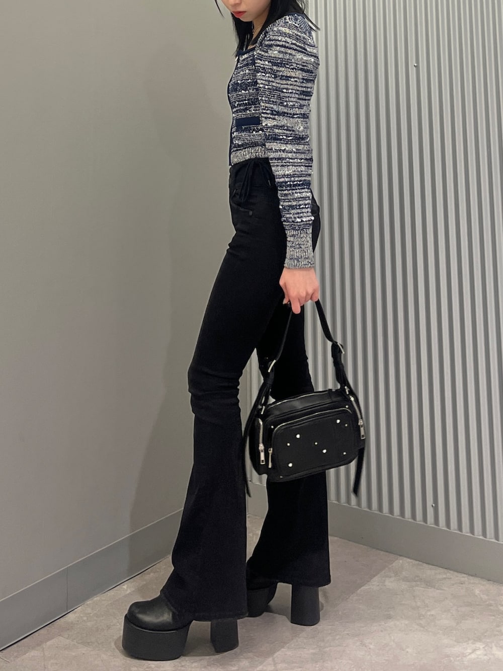 ブルー系のニット/セーター、ブラック系のデニムパンツ、ブラック系のショルダーバッグを着用したレディースの冬コーディネートの2枚目の写真