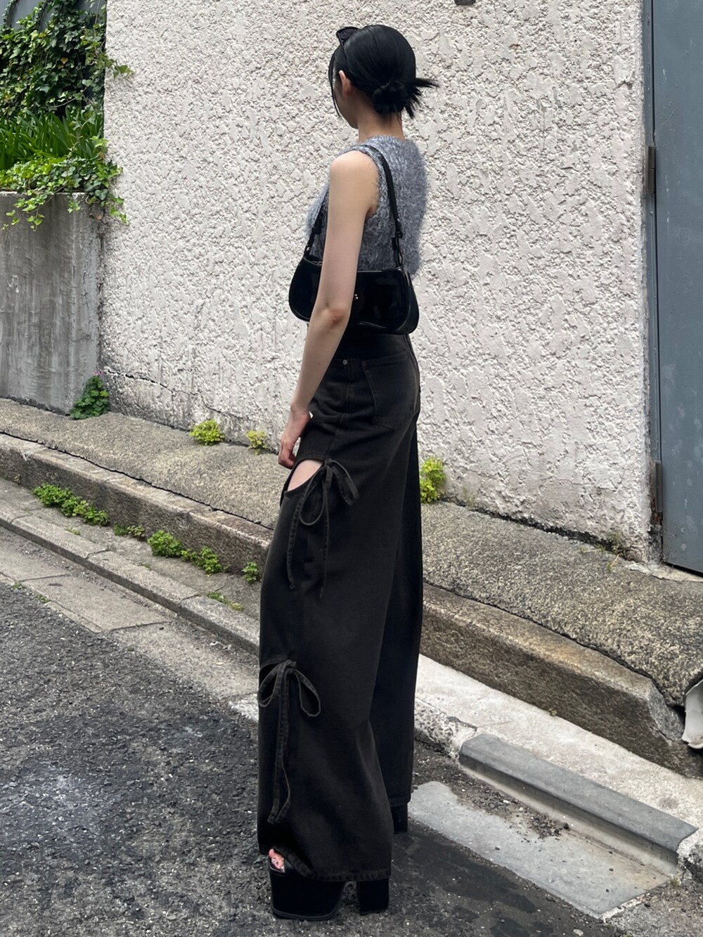 ブラック系のデニムパンツ、ブラック系のサンダル、グレー系のニット/セーターを着用したレディースの春コーディネートの2枚目の写真