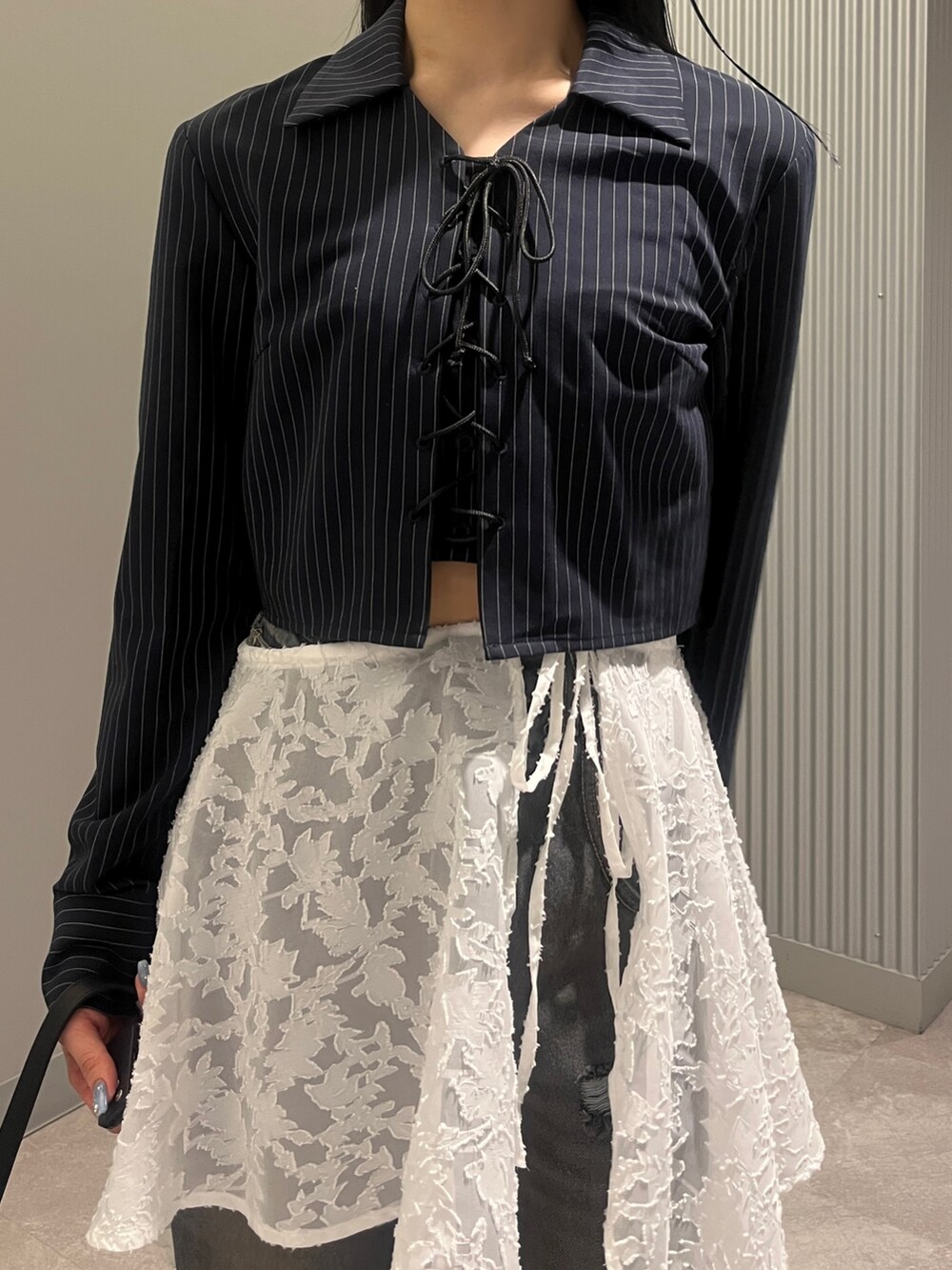 ブルー系のシャツ/ブラウス、ブラック系のハンドバッグ、ホワイト系のスカートを着用したレディースの春コーディネートの4枚目の写真