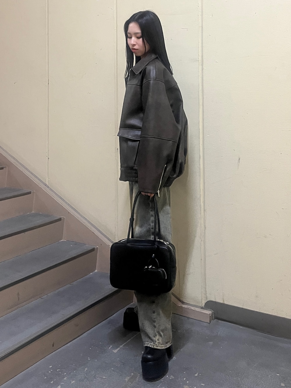 ブラック系のニット/セーター、ブラウン系のブルゾン、ブルー系のデニムパンツを着用したレディースの冬コーディネートの2枚目の写真