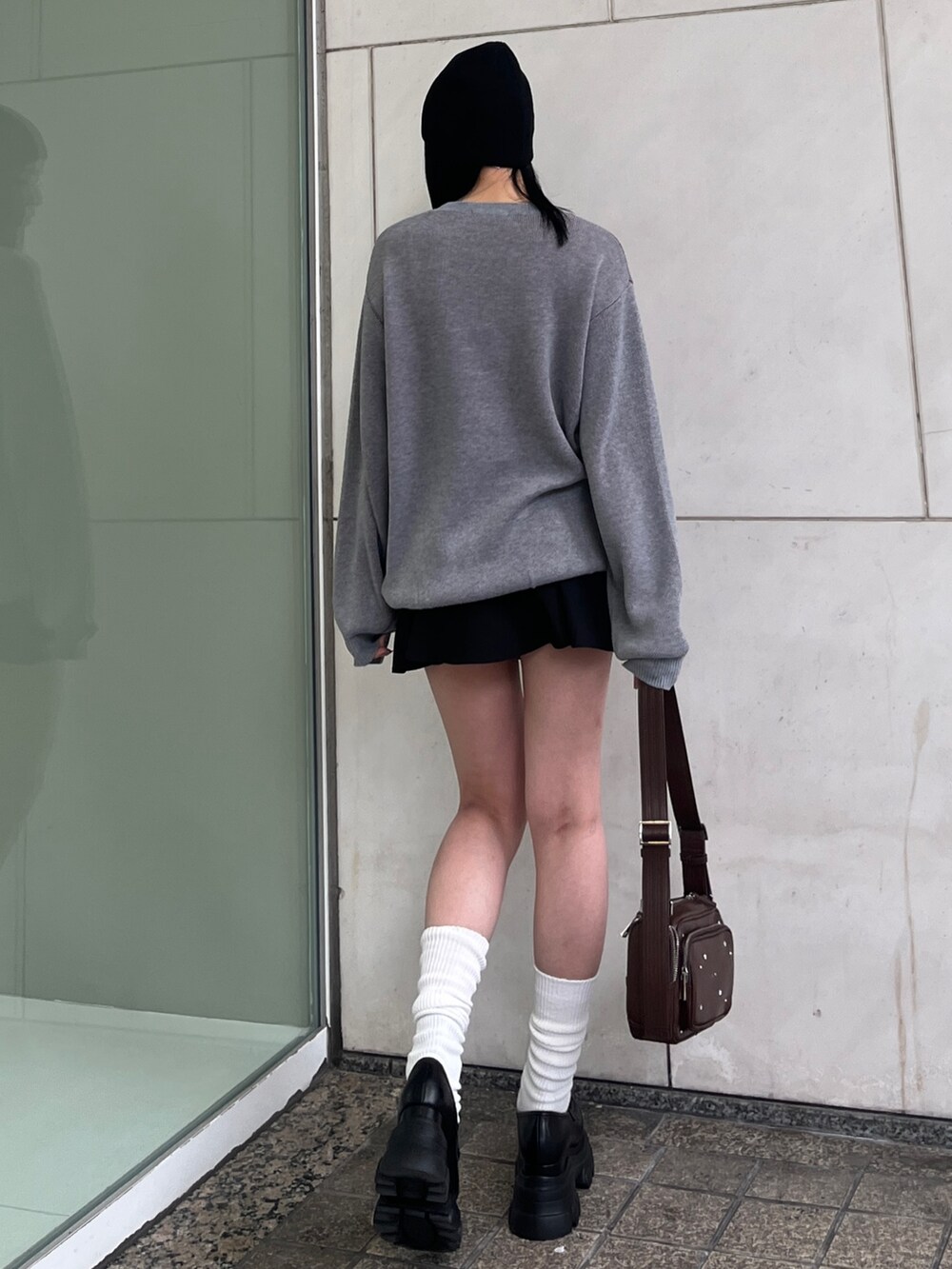 グレー系のニット/セーター、ブラック系のスカート、ブラウン系のショルダーバッグを着用したレディースの春コーディネートの3枚目の写真