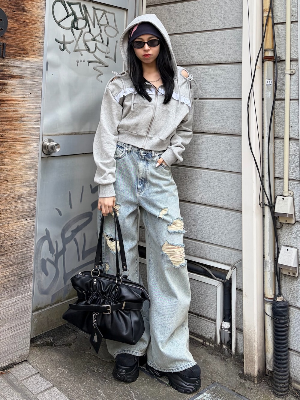 グレー系のパーカー、ブルー系のデニムパンツ、ブラック系のトートバッグを着用したレディースの春コーディネートの2枚目の写真