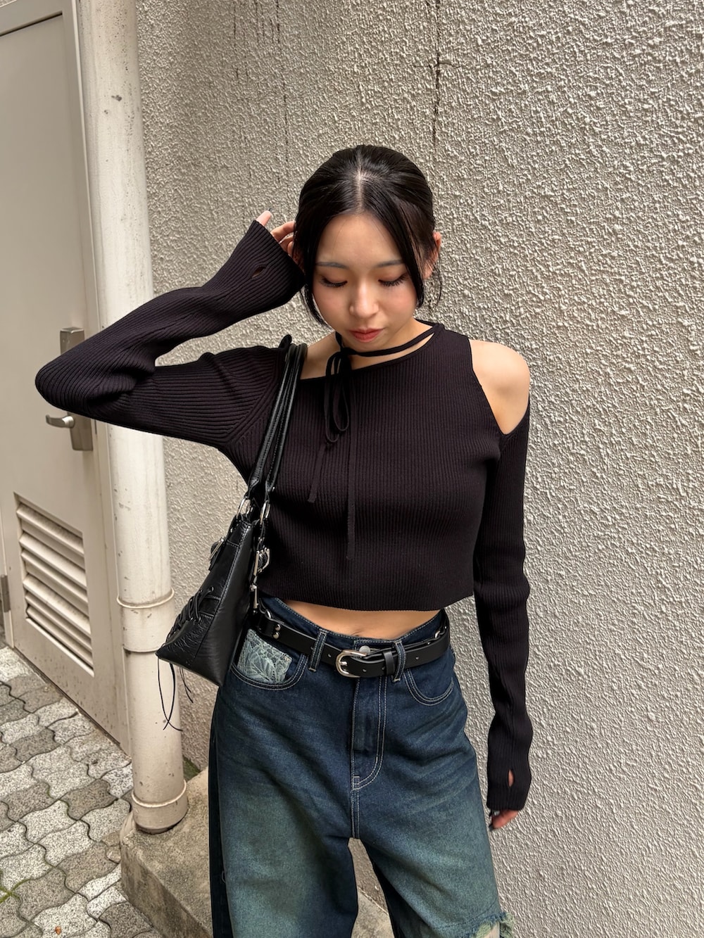 ブラック系のニット/セーター、ブルー系のデニムパンツ、ブラック系のショルダーバッグを着用したレディースの秋コーディネートの4枚目の写真