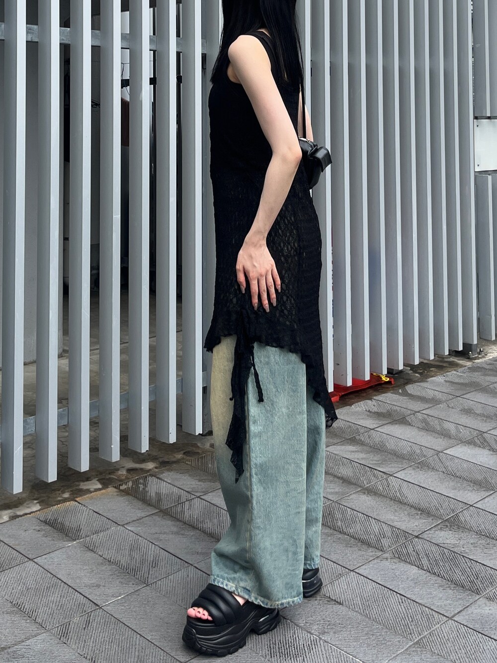 ブラック系のワンピース、ブルー系のデニムパンツ、ブラック系のサンダルを着用したレディースの夏コーディネートの2枚目の写真