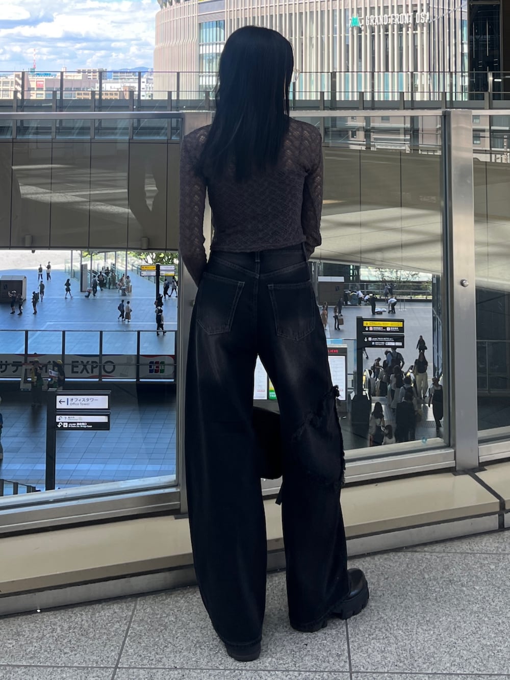 グレー系のTシャツ/カットソー、ブラック系のハンドバッグ、ブラック系のデニムパンツを着用したレディースの秋コーディネートの3枚目の写真