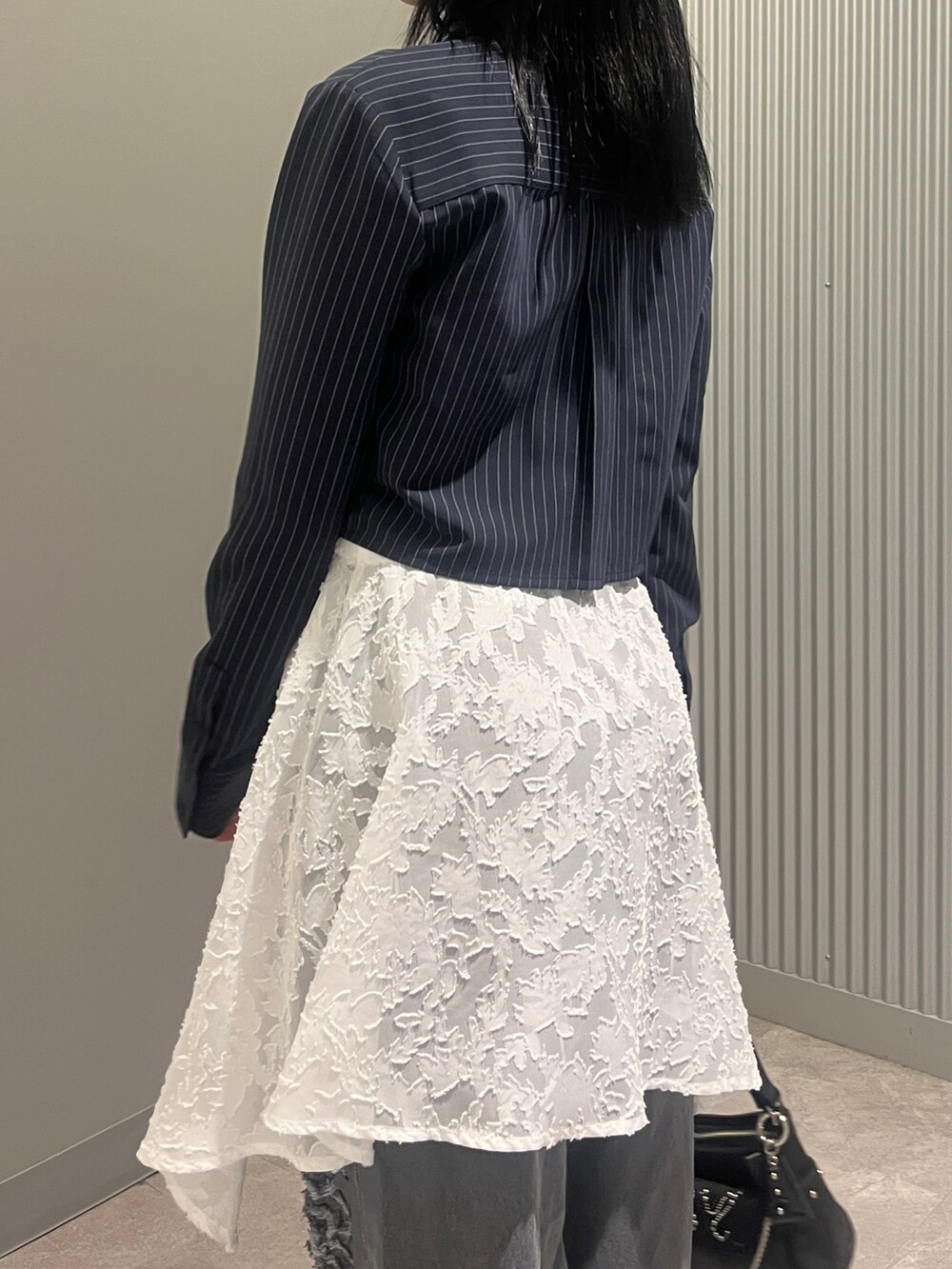 ブルー系のシャツ/ブラウス、ブラック系のハンドバッグ、ホワイト系のスカートを着用したレディースの春コーディネートの5枚目の写真