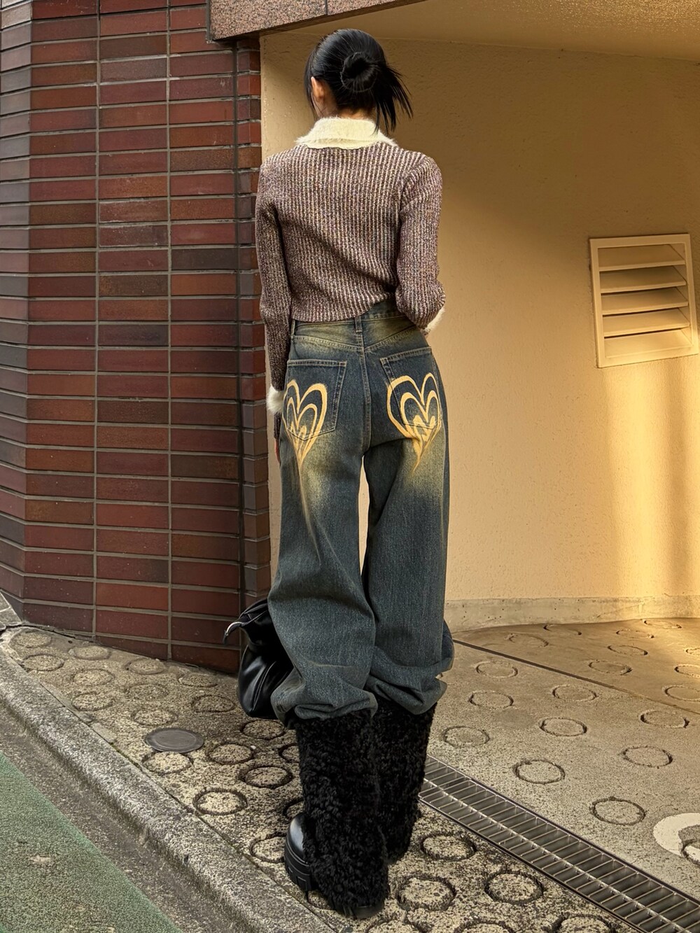 ブラウン系のニット/セーター、ブルー系のデニムパンツ、ブラック系のブーツを着用したレディースの冬コーディネートの3枚目の写真